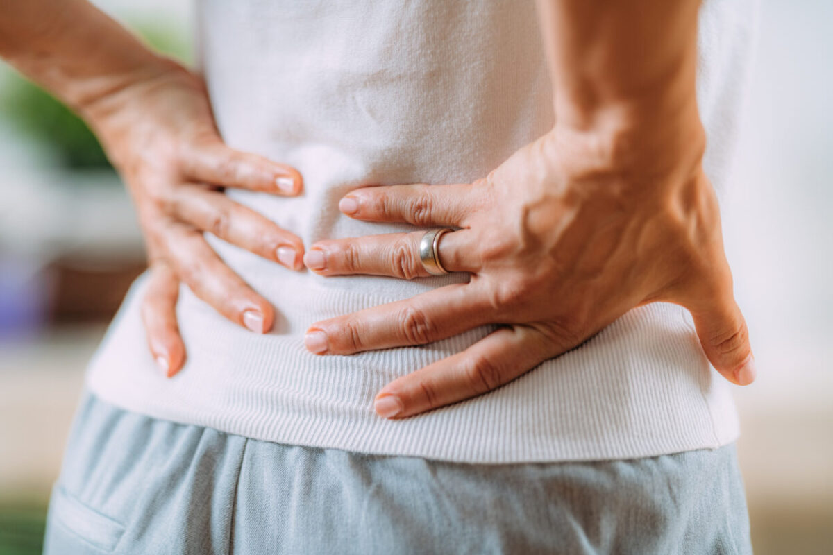 Close-up of hands holding lower back in pain