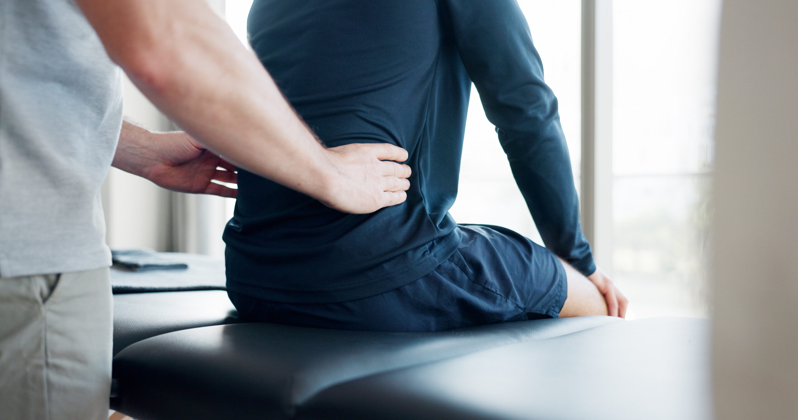 Therapist applying pressure to a client’s lower back during a massage session to relieve pain and tension