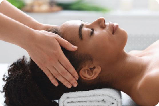 Woman receiving craniosacral therapy, lying on her back with a therapist’s hands gently cradling her head.