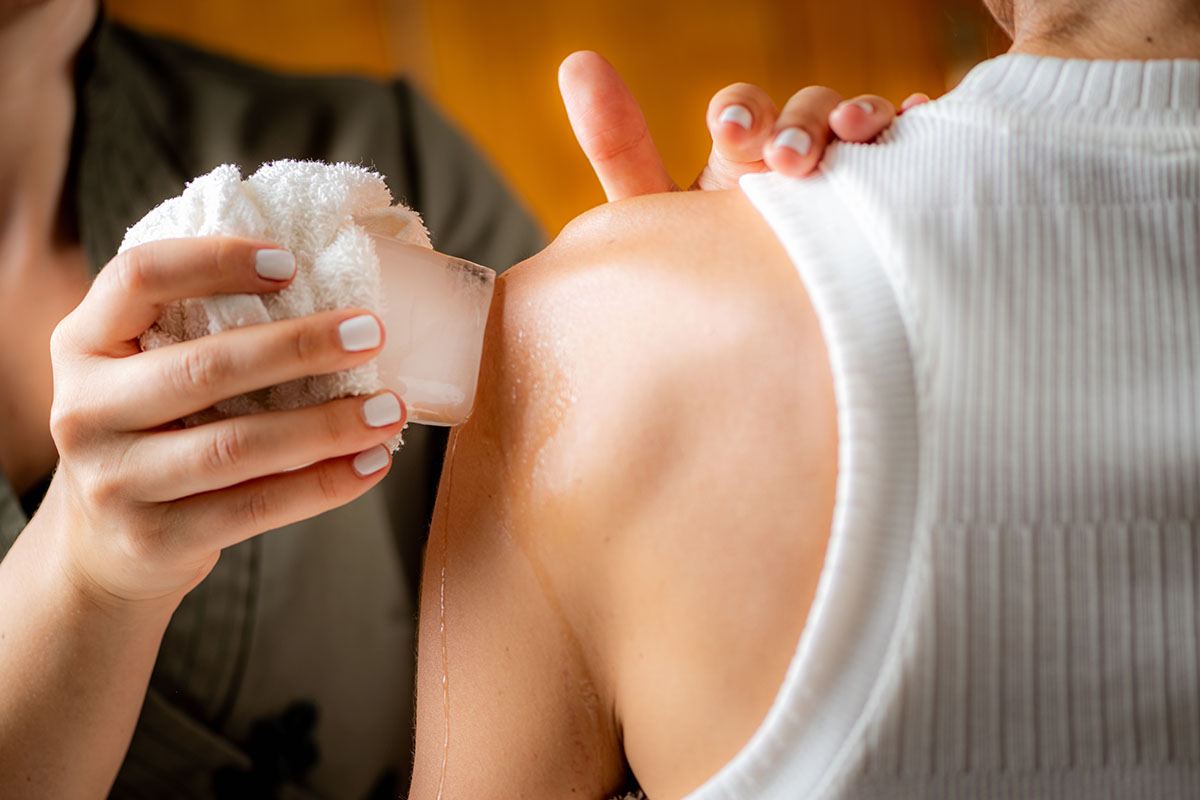 Woman receiving craniosacral therapy, lying on her back with a therapist’s hands gently cradling her head.