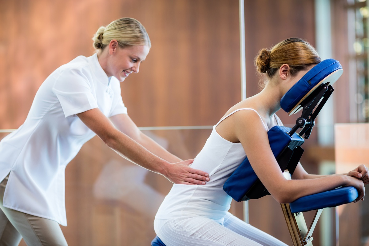 Therapist applying massage to a client’s lower back during an office chair massage