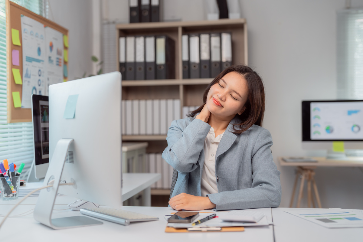 Female therapist giving chair massage in office to help employee relax
