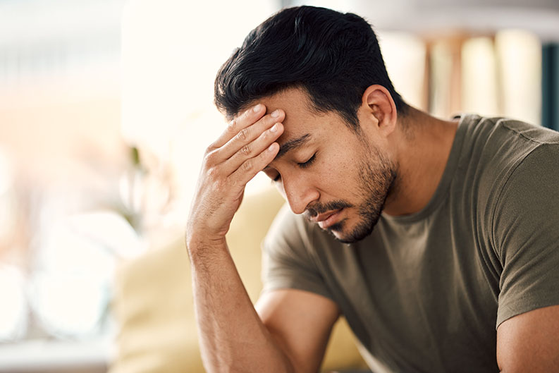 Man with hand on forehead looking distressed, illustrating the link between deep tissue massage and mental health beyond stress and anxiety