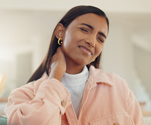 Woman experiencing neck pain after a deep tissue massage, holding her neck with a pained expression