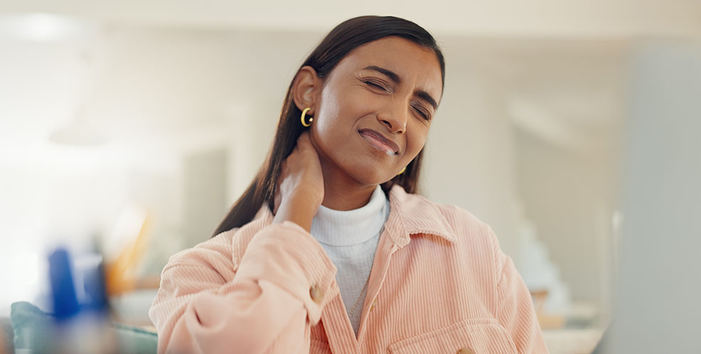 Woman experiencing neck pain after a deep tissue massage, holding her neck with a pained expression