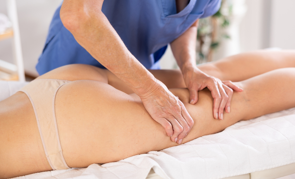 Therapist massaging the thigh muscles of a client to release tension and improve circulation.