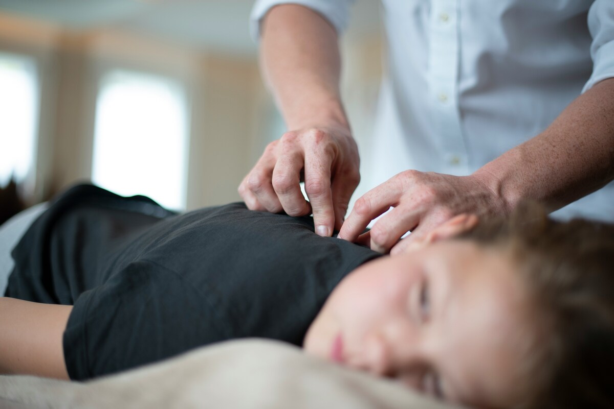 Close-up of therapist’s hands applying pressure along a client’s back muscles for pain relief.